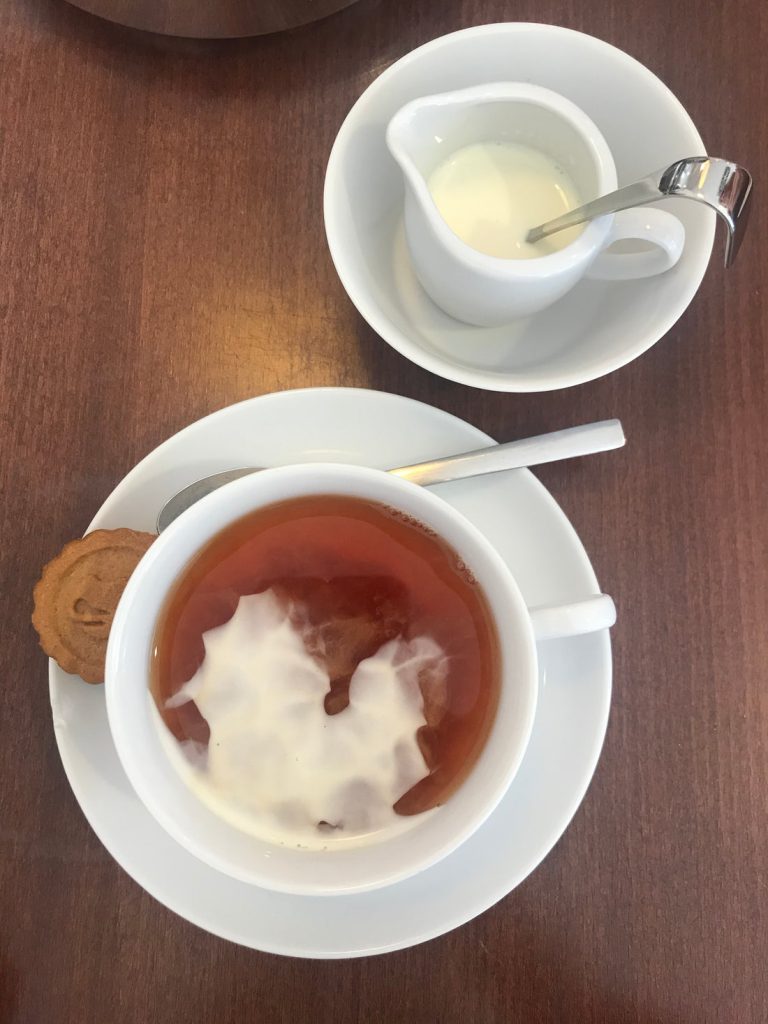 Kop thee met een scheut melk en een koekje, van bovenaf gezien